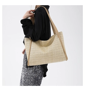 Detail of woven straw tote bag featuring brown leather shoulder straps and large capacity