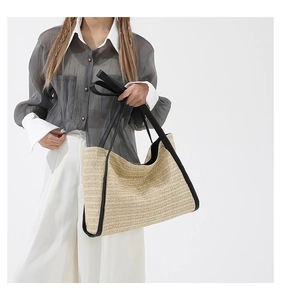 Detail view of contrast color straw tote bag with black faux leather trim and straps