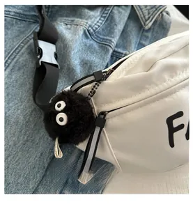 Detail of a white nylon crossbody bag with a fuzzy black soot sprite bag charm accessory