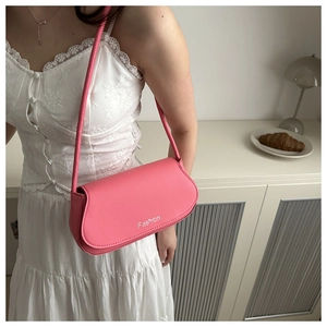Detail of pink saddle bag with Fashion text, worn by model in white lace dress