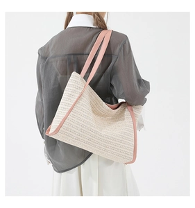 Detail of a large woven tote bag with pink faux leather trim and sturdy shoulder straps