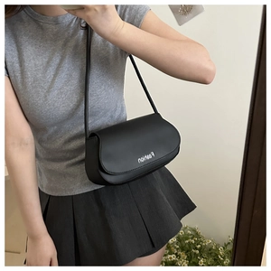 Model wearing a black leather saddle bag with white fashion print under the arm