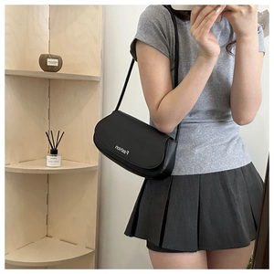 Detail of minimalist black saddle bag with Fashion text and premium matte finish