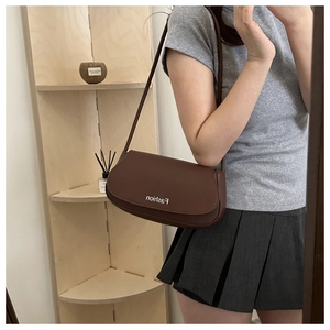 Mirror selfie showing a dark brown saddle bag with Fashion text and slender strap
