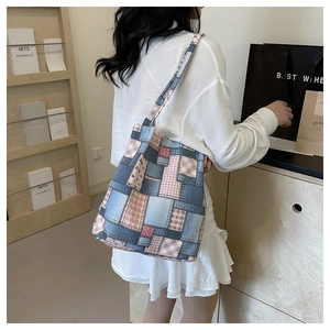 Detail of patchwork denim tote bag with pink plaid heart pattern on a shoulder strap