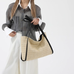 Large beige woven straw tote bag with black leather handles and trim for women