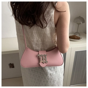 Pink leather baguette bag with silver gothic buckle shown on model in cozy interior