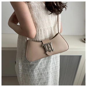 Close-up of beige baguette underarm bag with silver gothic metal letter buckle