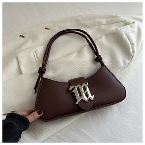 Detail of dark chocolate baguette bag with silver M buckle on white textured blazer