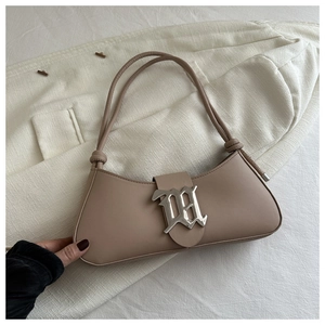 Detail of apricot baguette bag featuring a silver metal M-shaped decorative buckle