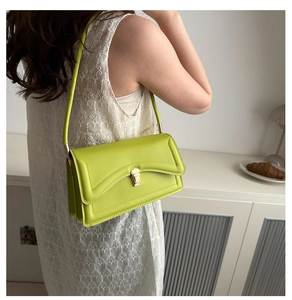 Detail of lime green faux leather shoulder bag featuring a metal twist lock and slim handle