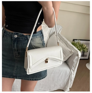 Detail of white envelope crossbody bag with gold buckle and curved stitching accents