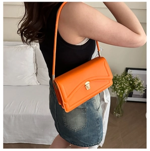 Detail of bright orange shoulder bag with geometric stitching and gold metal lock