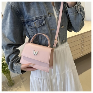 Pink mini crossbody bag featuring a silver butterfly buckle and adjustable leather strap