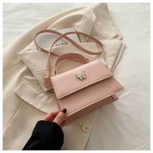 Detail of pink leather handbag with enamel butterfly clasp on a beige blazer