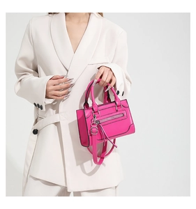 Détail d'un sac à main rose vif en cuir avec finitions argentées sur blazer crème