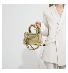 Détail d'un sac à main doré métallisé avec poignées cylindriques et décor de fermeture
