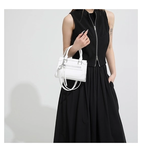 Petit sac blanc porté en bandoulière avec une tenue noire pour un style minimaliste