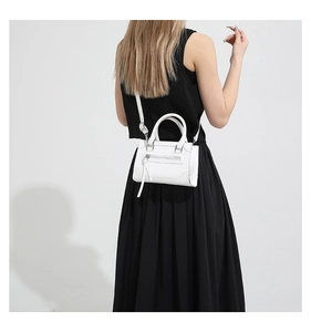 Vue détaillée du modèle portant un sac blanc avec une robe longue plissée noire
