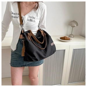 Detail of a large black canvas tote bag featuring brown handles and Fashion label tag