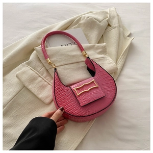 Dettaglio pelle a trama coccodrillo e chiusura dorata su borsa baguette rosa vivace