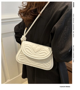 Detail of white quilted leather shoulder bag featuring V-shaped stitching and heart pattern