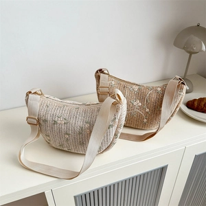 Woven dumpling shoulder bag with floral embroidery and adjustable canvas strap