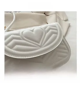 Close-up of white heart quilted leather flap bag with elegant V-shaped stitching details