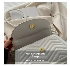 Detail of the golden magnetic hardware buckle on a white quilted saddle bag
