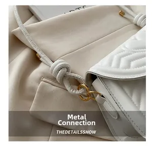 Detail of white quilted handbag featuring gold ring metal hardware and knotted strap
