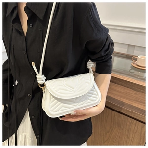 Detail of white quilted leather shoulder bag featuring heart and chevron stitching patterns