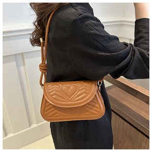 Detail of heart-shaped quilting and V-stitch on brown faux leather shoulder bag