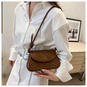 Caramel brown crossbody bag with heart quilting and V-pattern on a white shirt background