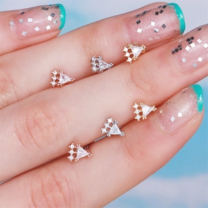 Close-up of triangular zircon cartilage studs in gold, silver and rose gold finishes