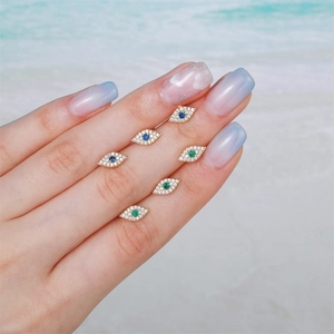 Evil eye stainless steel stud earrings with zircons shown on a hand at beach