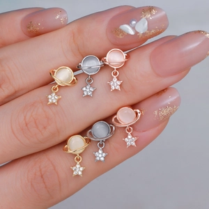 Orecchini a pianeta con pendenti a stella in oro, argento e oro rosa mostrati sulla mano