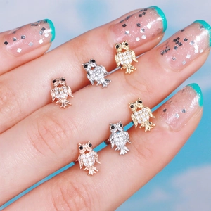 Detailed close-up of crystal owl ear studs in gold, rose gold and silver finish