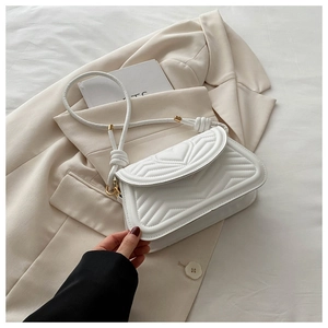 Detail view of white quilted underarm bag with heart stitching and gold hardware