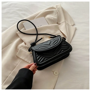 Detail of black quilted shoulder bag with heart and V-shaped patterns on leather surface