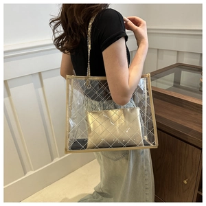Détail du sac cabas en PVC transparent avec coutures dorées et bandoulière chaîne