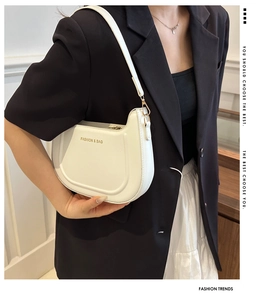 Dettaglio della borsa a spalla bianca a semicerchio con logo dorato e zip elegante
