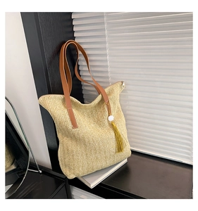 Vue détaillée d'un sac en paille tissée avec anses en cuir marron et pendentif à glands