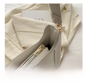 Dettaglio di una borsa baguette bianca con cuciture verticali e cerniera dorata lucida