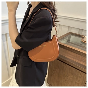 Modella che indossa una borsa a spalla a mezzaluna in pelle color cuoio e oro