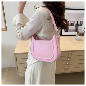 Dettaglio borsa hobo rosa con logo dorato sulla spalla di una modella in casa