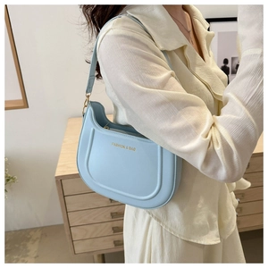 Dettaglio borsa a spalla azzurra con scritta dorata FASHION & BAG e design curvo
