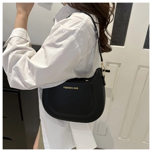 Dettaglio della borsa a mezzaluna in pelle nera con logo dorato portata a spalla
