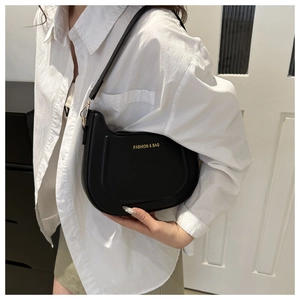 Dettaglio della borsa a sella in pelle PU nera con hardware dorato e scritta fashion