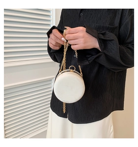 Detailed view of white marble texture round chain bag with golden metal frame