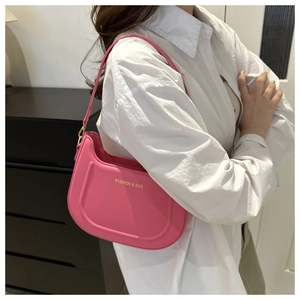 Borsa hobo in pelle rosa acceso con scritte dorate indossata su camicia bianca
